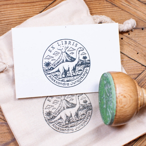 Stempel ex libris z dinozaurem – odbicie pieczątki na kartce i woreczek