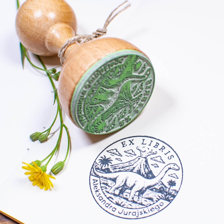 Drewniany stempel ex libris z dinozaurem – ujęcie z kwiatem