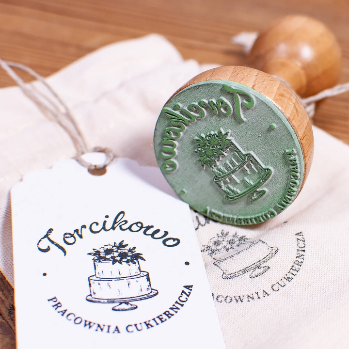 Drewniany stempel, personalizowana gumka, bawełniany woreczek oraz opcjonalna poduszka z tuszem w wybranym kolorze.